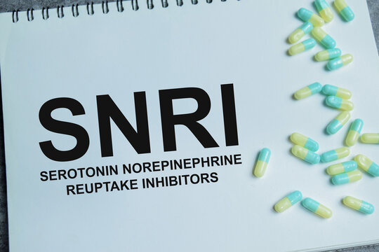Concept of SNRI - Serotonin Norepinephrine Reuptake Inhibitors write on book isolated on Wooden Table. For antidepressant medication and mental health treatment