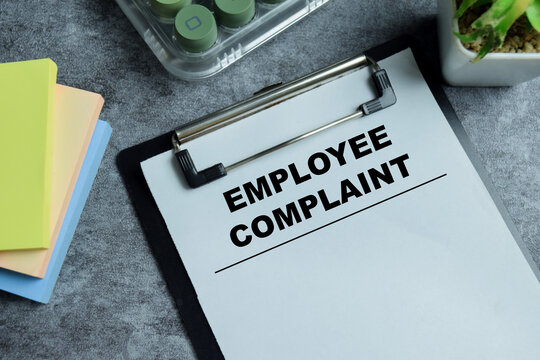 Concept of employee complaint write on clipboard isolated on Wooden Table. For human resource conflict resolution and office stress