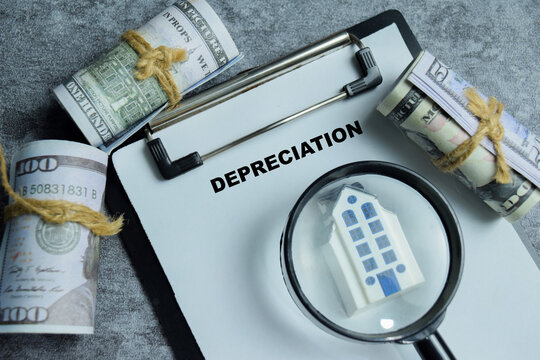 Concept of property depreciation write on clipboard isolated on Wooden Table. For real estate market decline and rent value reduction