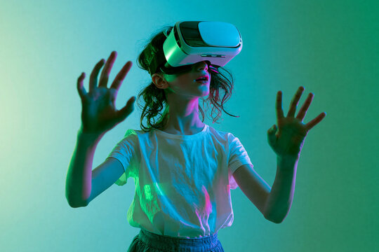  Menina crian&ccedil;a usando &oacute;culos de realidade virtual tocando no ar com luzes neon. Conceito de metaverso, jogos e tecnologia do futuro