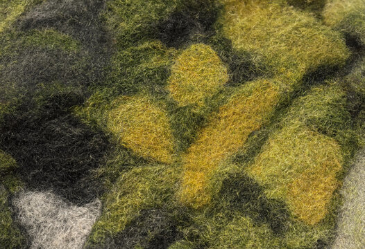 Close up texture of green and yellow felted moss wool for sustainable eco friendly textile background