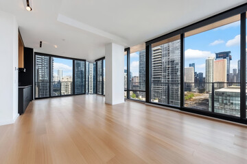 Fototapeta premium Bright empty apartment with floor to ceiling windows offering panoramic city views, showcasing urban living potential