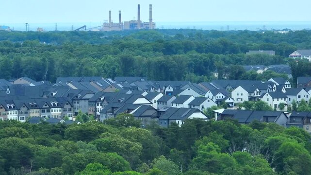 Twin houses set between the forest and a factory in the background&mdash;nature and industry coexist.