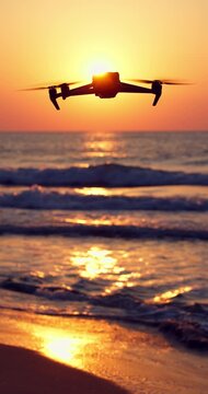 Ocean beach sunrise and flying drone above sea waves against the sun
