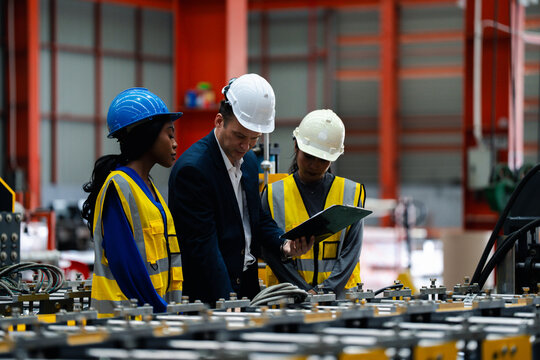 woman worker and engineer under inspection and checking production process on factory station. Factory Engineer. Professional Heavy Industry Engineer Worker. Team of factory workers.