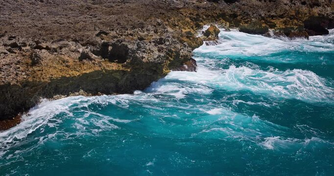Turquoise ocean waves crashing against rocky coastline with sea foam