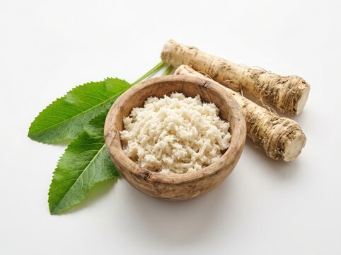 Fresh horseradish root with grated wasabi paste in a small wooden bowl and green leaves for cooking and seasoning isolated on white background