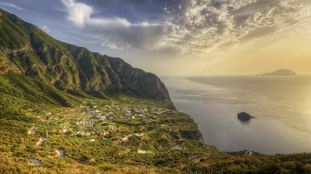 Pollara Bay, Salina island, view of a village on a steep coast surrounded by mountains and golden sunset light, UNESCO World Heritage Site, Aeolian Islands, Aeolian Islands, Sicily, Italy