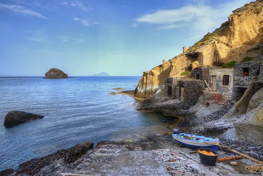 Houses in the rock, pebble beach, boat, sandstone rocks, Filicudi, Scoglio Faraglione, Spiaggia di Pollara, Pollara beach, Pollara, Salina, Aeolian Islands, Sicily, Italy