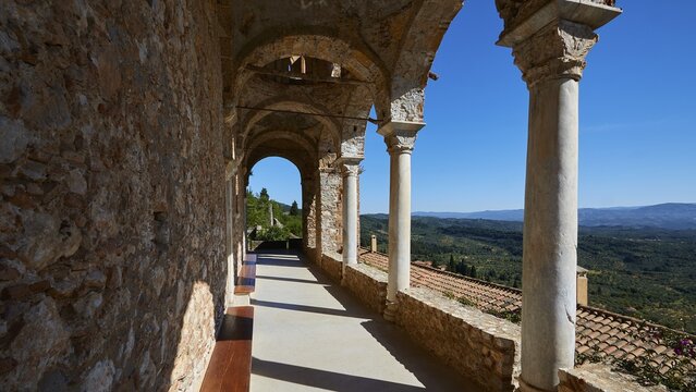 Pantanassa Monastery from the 15th century AD, stone arcade with columns offers views of the landscape under a bright blue sky, Mystras, Mistra, UNESCO World Heritage Site, medieval Byzantine ruined city, north-west of Sparta, foothills of the Tyagetos Mountains, Peloponnese, peninsula, Greece