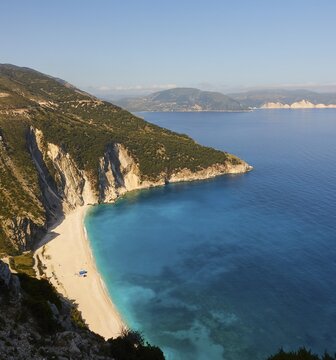 Myrtos Beach, view from above, white sandy beach, bay in cliff, overgrown slopes, blue and turquoise sea, blue almost cloudless sky, Kefalonia Island, Ionian Islands, Greece