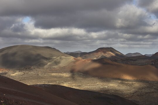 Different coloured lava hills, Timanfaya National Park, fire mountains, volcanic landscape, cloudy sky, play of light and shadow, Lanzarote, Canary Islands, Spain