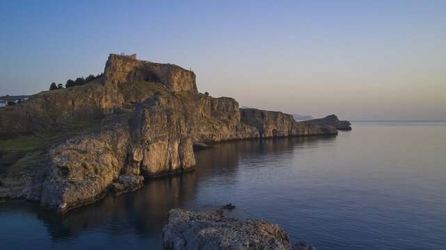 Drone shot, first morning light, Lindos, Acropolis of Lindos, Picturesque castle on a cliff overlooking the sea caught in the stillness of dusk, Archaeological site, Lindos, Rhodes, Dodecanese, Greek Islands, Greece