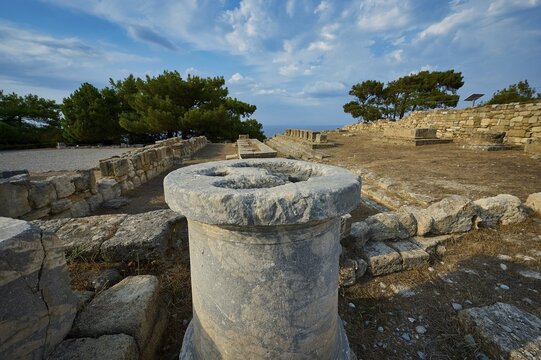 Stone column in the middle of an ancient ruins field with trees and stone structures in the background, Exedra, Kamiros, Archaeological site, Ancient city, Foundation of Doric Greeks, Rhodes, Dodecanese, Greek Islands, Greece