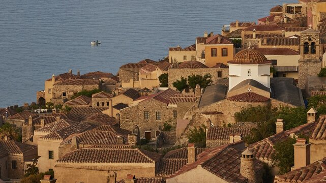 Soft morning light, Holy Church of the Virgin Mary Myrtidiotissa (or Kritikias), view of a historic seaside fishing village with tiled roofs and a small boat in the water, Monemvasia, Monemvassia, Malvasy, Byzantine small town, rocky island, fortress, Laconia, Peloponnese, peninsula, Greece