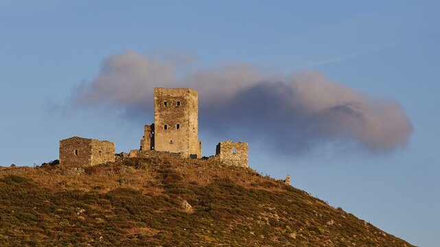 Sunset colours the clouds over the imposing ruins of a fortress on a mountain, residential tower on a mountain, Mani peninsula, Peloponnese, Greece
