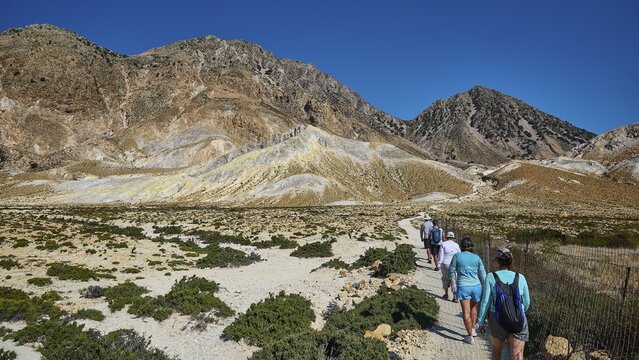 People walking on a path through a mountainous landscape under a clear sky, volcanism, volcanic island, Polyvotis crater, Nisyros, Dodecanese, Greek Islands, Greece