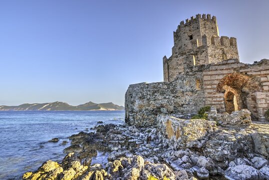 HDR photo of an old castle on the coast with blue sky and mountains in the background, octagonal medieval tower. Islet of Bourtzi, sea fortress Methoni, Peloponnese, Greece