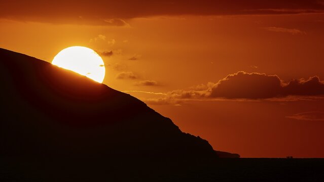Sun disappears behind mountain, bright warm orange sky at sunset, sunset, Kassos, Karpathos, offshore islands, Dodecanese, Greek Islands, Greece