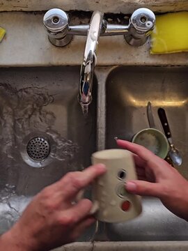 Manos lavando platos y tazas en la cocina