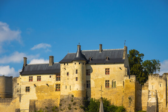 Majestic medieval French castle with stone towers on a beautiful autumn day in France. Ancient chateau fortress under a blue sky with clouds.