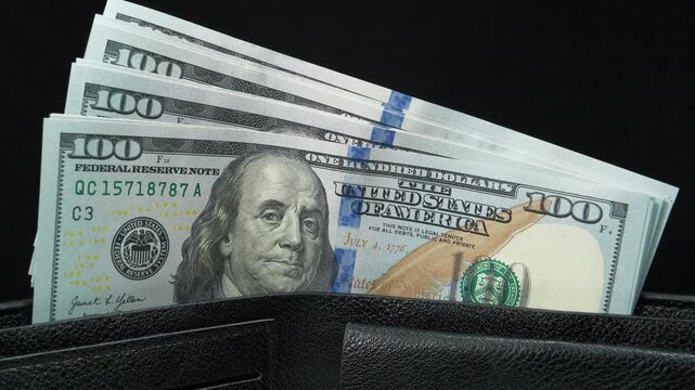 A wad of american dollars in wallet. 100 dollars banknotes in a black wallet. Cash, finance, savings, wealth. New 100 dollar bills, USD