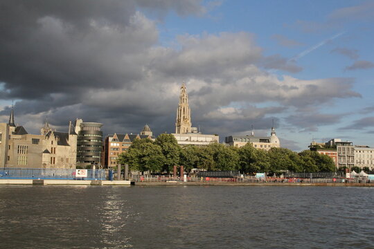 the skyline of antwerp with the quay of the linkeroever and the tower of the church and apartment buildings and office buildings along the western scheldt