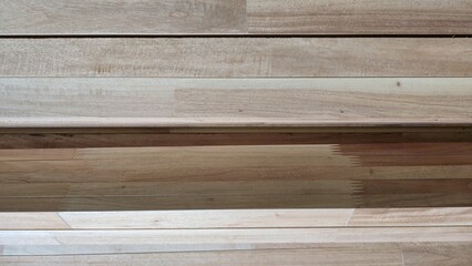 Fototapeta premium Natural lumber planks stacked horizontally texture background. Close-up of raw wooden framing boards stacked together, showcasing organic timber lines and material setup.