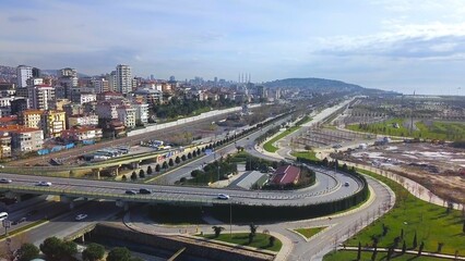 Aerial drone view of a newly constructed multi-level interchange on Maltepe coastal road with light vehicle traffic, residential buildings, green areas and partly cloudy spring sky, Istanbul, Turkey © Faraways