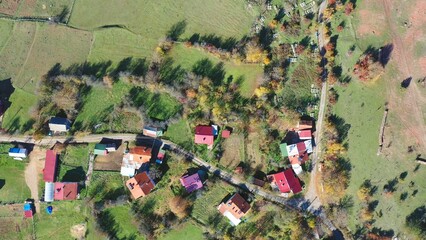 Colorful rooftops of a Mengen village scattered amid green pastures and autumn trees, overhead aerial view. Bolu, Turkey. Aerial view, drone shot © Faraways