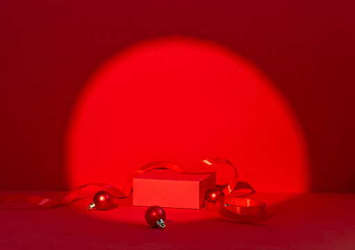 Red Christmas Gift Scene with Ornament Balls and Ribbon Under Circular Spotlight on Red Background