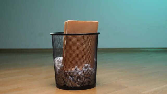 Office wastebasket filled with crumpled paper and old brown files, illustrating concepts of waste management, disposal, archiving, and decluttering an workspace environment