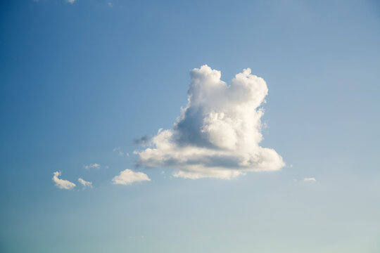 Fluffy white clouds float serenely above, contrasting beautifully against a deep brilliant blue sky, creating a magical and cozy atmosphere.