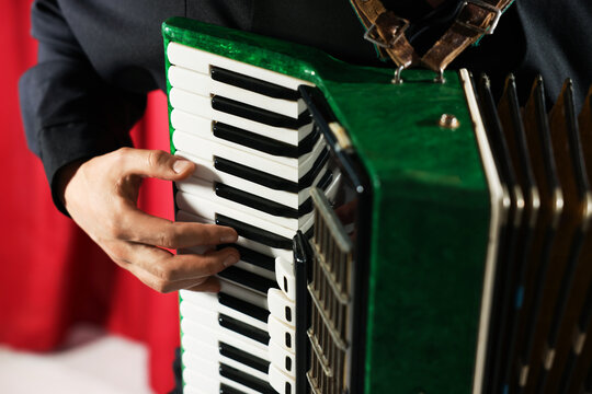 Man playing piano accordion on stage, closeup