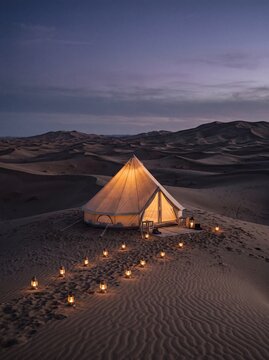 Luxury glamping bell tent illuminated by lanterns in the desert at twilight