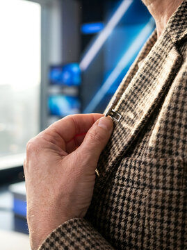 Primer plano de una mano colocando un micr&oacute;fono de solapa en la chaqueta de un presentador en un estudio de televisi&oacute;n