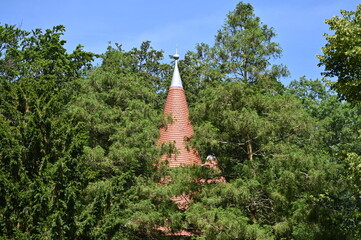 Roof tiles on a pointed turret and green trees © andsyphoto