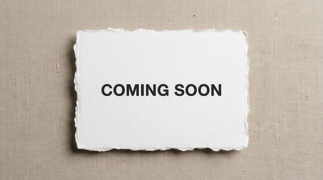 White torn edge paper card with coming soon text on a beige linen fabric surface