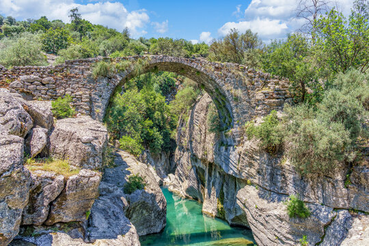 Ancient Roman stone bridge Oluk over Koprucay river in Koprulu Canyon national park, Antalya, Turkey. Scenic view of the historic Oluk bridge arching over a turquoise mountain river stream