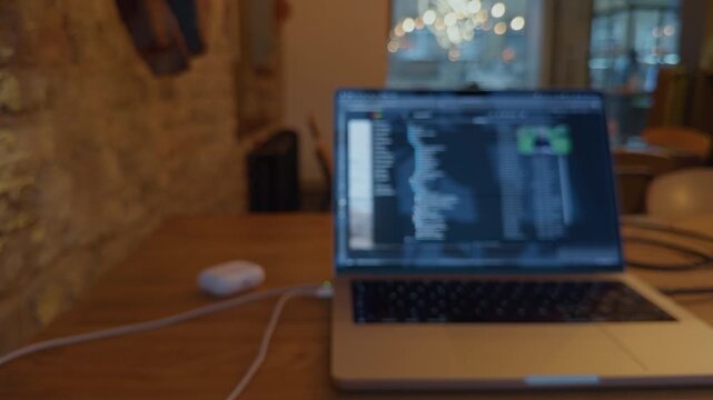 Blurred laptop with code editor open on wooden desk in warm home office workspace