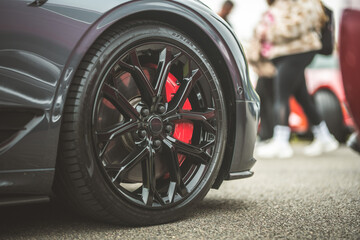 Close-up of a sleek black sports car wheel with vibrant red brake calipers © Pavel Babic