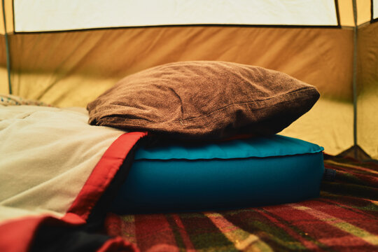 Camping pillows on a plaid blanket inside a tent