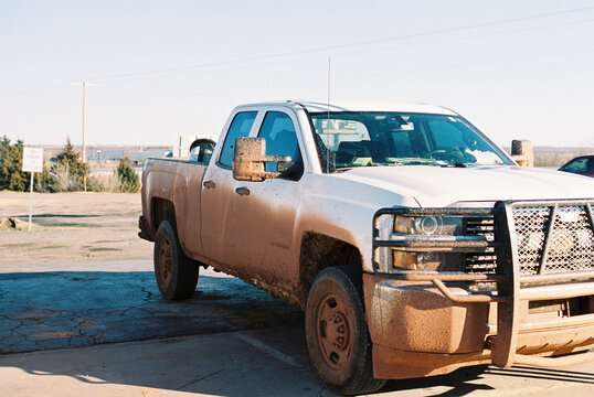 Heavy Duty Mud-Caked Chevrolet Silverado Work Truck Parked in a Flat Rural Landscape, Shot on Film