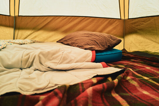 Cozy tent interior with sleeping bag and plaid blanket
