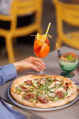 Fototapete Pizzeria Friends toasting with cocktails and wine over pizza People celebrating with drinks in Italian restaurant Cheers with Aperol Spritz and wine during dinner  © Mykhailo Feriukov