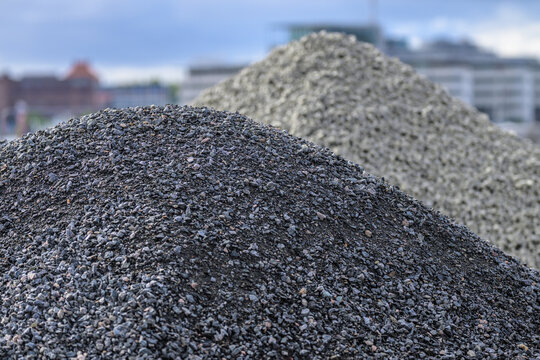 Dark gravel piles at urban construction site with skyline.