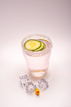 gin tonic in a glass with sugar rim a rubber dick and ice cubes in front of the glass