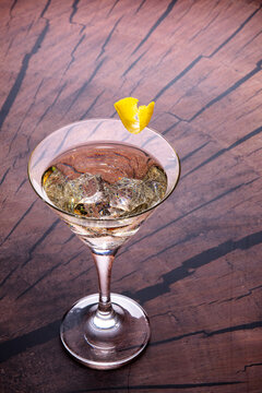 golden martini with icecubes and lemon cest as a garnisch on wooden background.