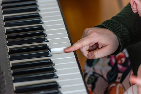 Child hand pressing piano keys learning music.
