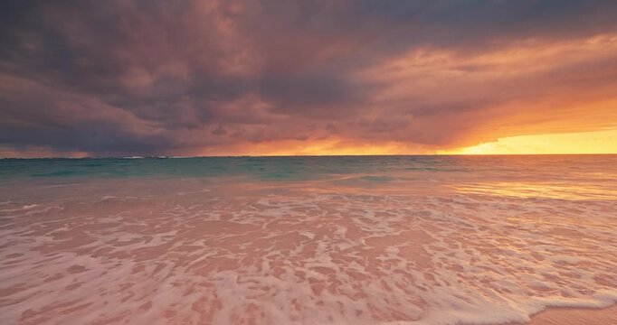 Tropical sunset over ocean beach splashing waves on the shore and and cloudy sky